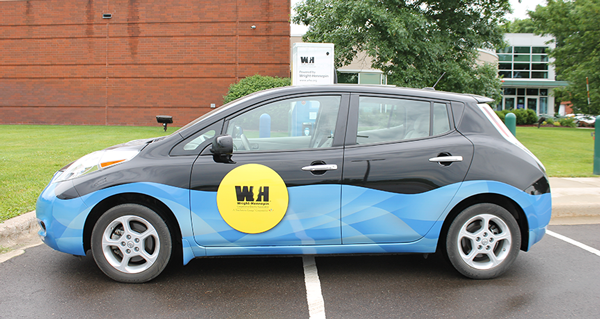 Wright-Hennepin's Nissan Leaf in front of its charger located in Rockford, MN. 