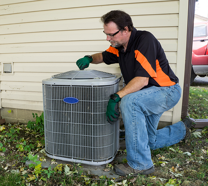 Technician inspecting/maintaining an air conditioner unit. 
