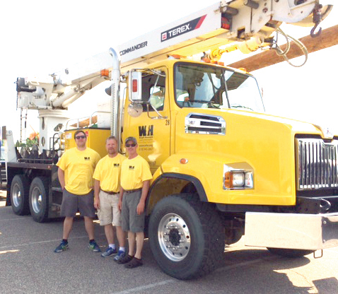 Three WH employees standing next to a line truck at the Annandale Fourth of July Parade. 