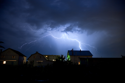 Lightning flashing over homes at night. 