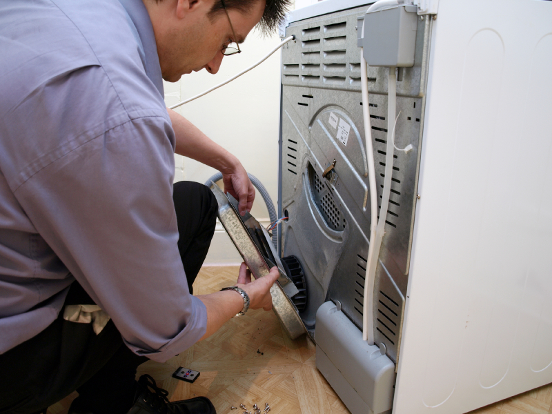 Technician repairing an electric dryer. 