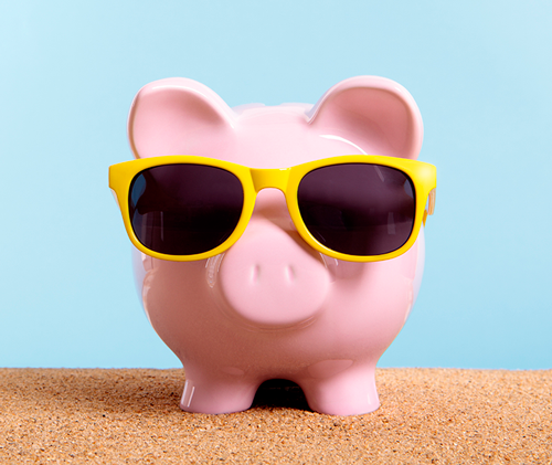 Piggy bank wearing sunglasses on a beach. 